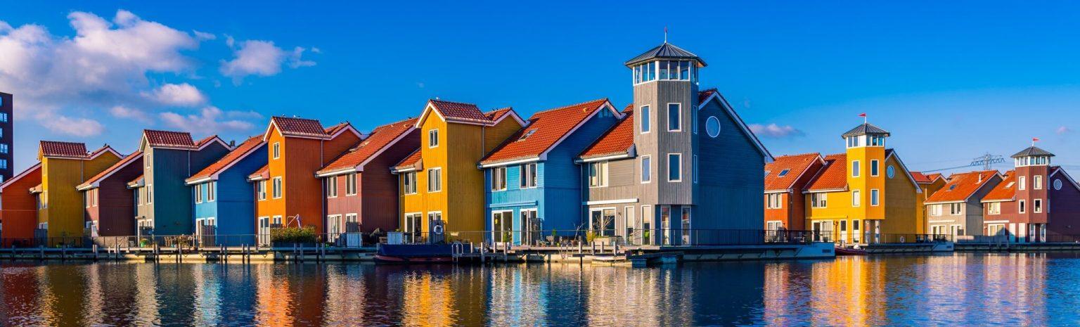 Portfolio 1 Kleurrijke huisjes aan de Reitdiephaven in Groningen weerspiegelen in het kalme water, met een serene sfeer die perfect is voor stadsfotografie.