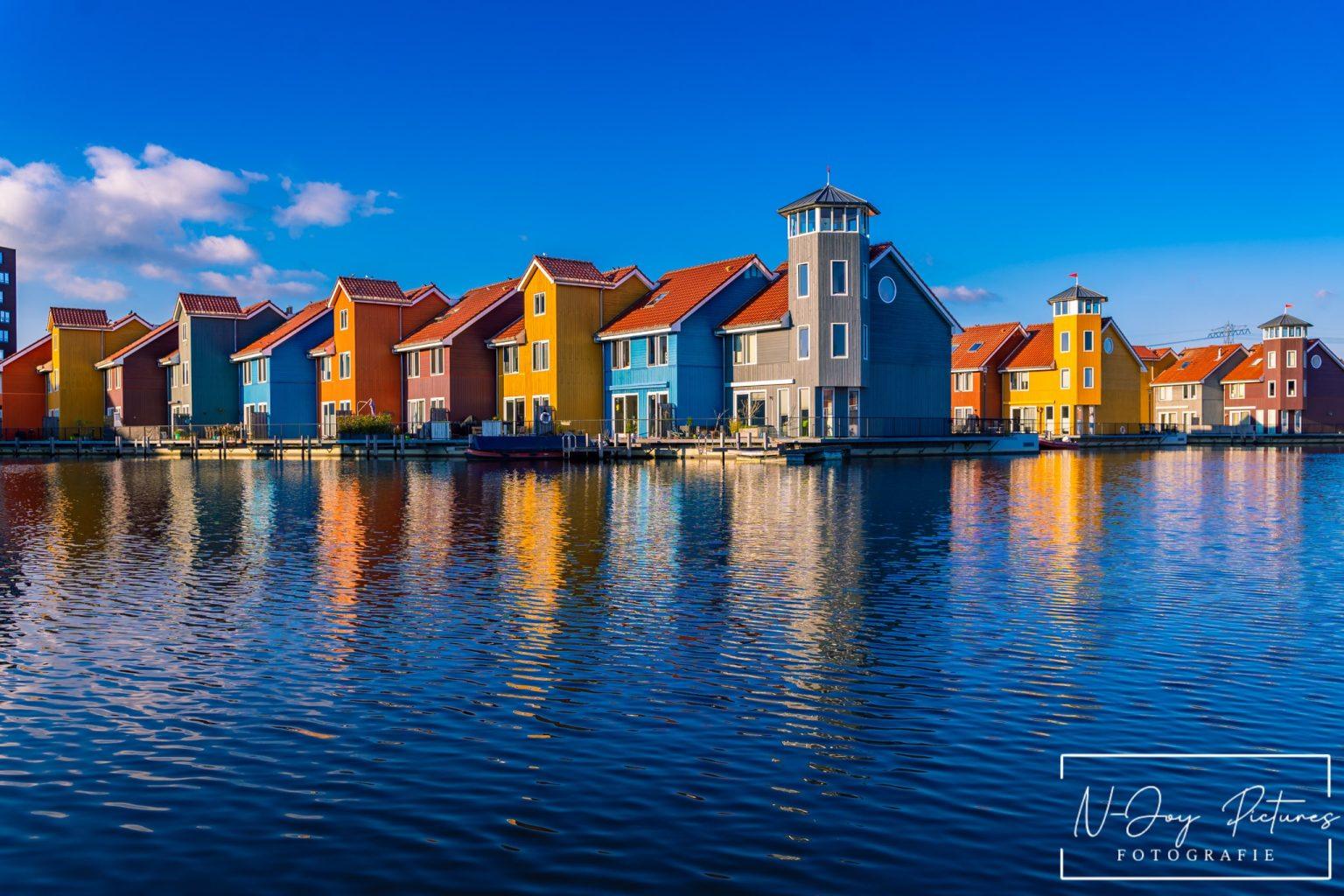 Kleurrijke huisjes aan de Reitdiephaven in Groningen weerspiegelen in het kalme water, met een serene sfeer die perfect is voor stadsfotografie.