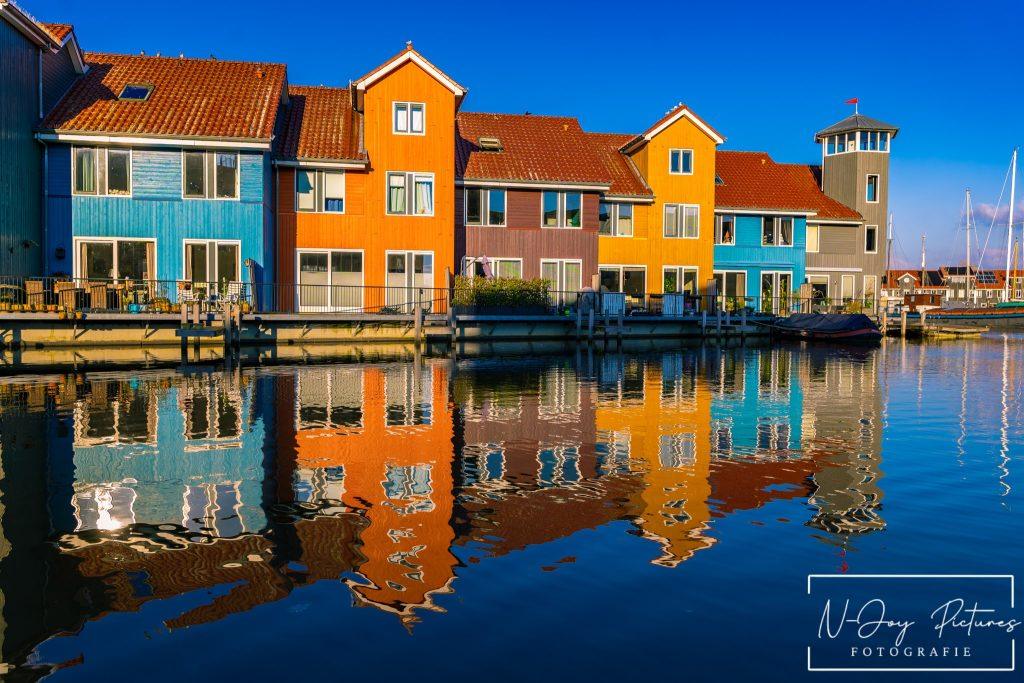 Levendige Plekken van Reitdiephaven Groningen Ontmaskerd! 5 Kleurrijke huisjes aan de Reitdiephaven in Groningen weerspiegelen in het kalme water, met een serene sfeer die perfect is voor stadsfotografie.