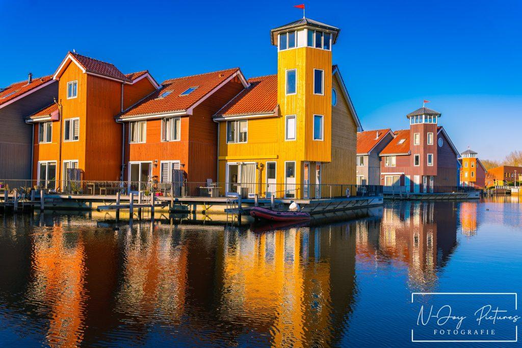 Levendige Plekken van Reitdiephaven Groningen Ontmaskerd! 10 Kleurrijke huisjes aan de Reitdiephaven in Groningen weerspiegelen in het kalme water, met een serene sfeer die perfect is voor stadsfotografie.
