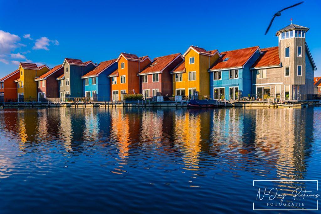 Kleurrijke huisjes aan de Reitdiephaven in Groningen weerspiegelen in het kalme water, met een serene sfeer die perfect is voor stadsfotografie.