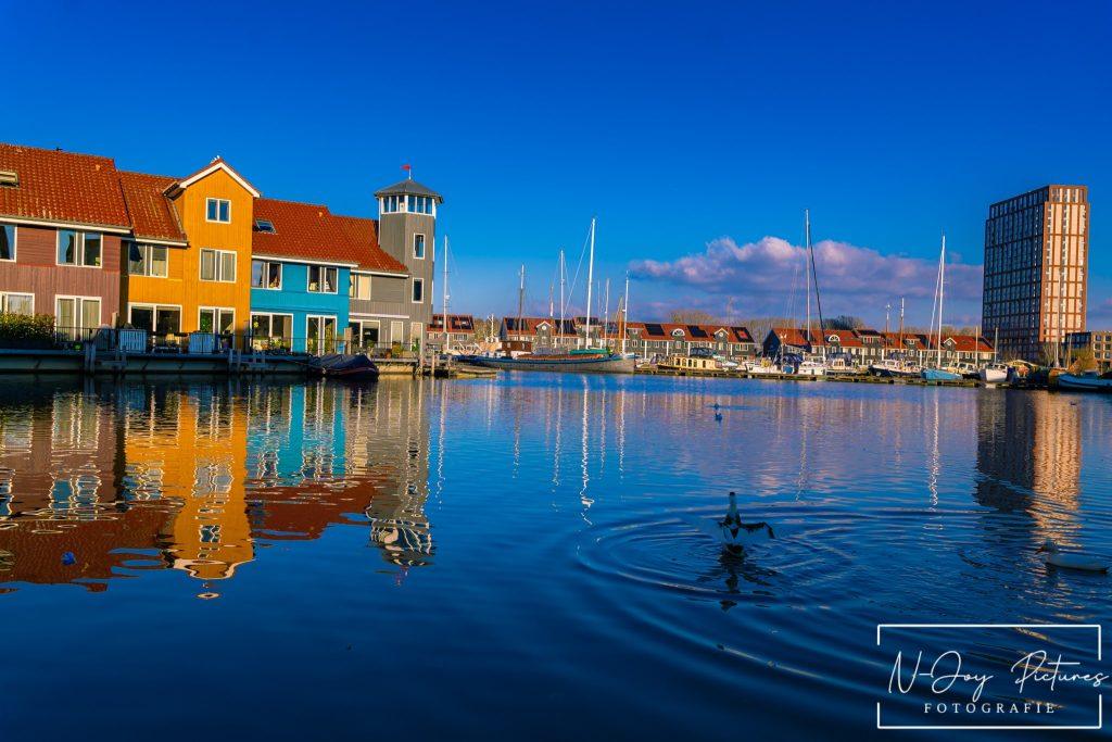 Levendige Plekken van Reitdiephaven Groningen Ontmaskerd! 8 Kleurrijke huisjes aan de Reitdiephaven in Groningen weerspiegelen in het kalme water, met een serene sfeer die perfect is voor stadsfotografie.