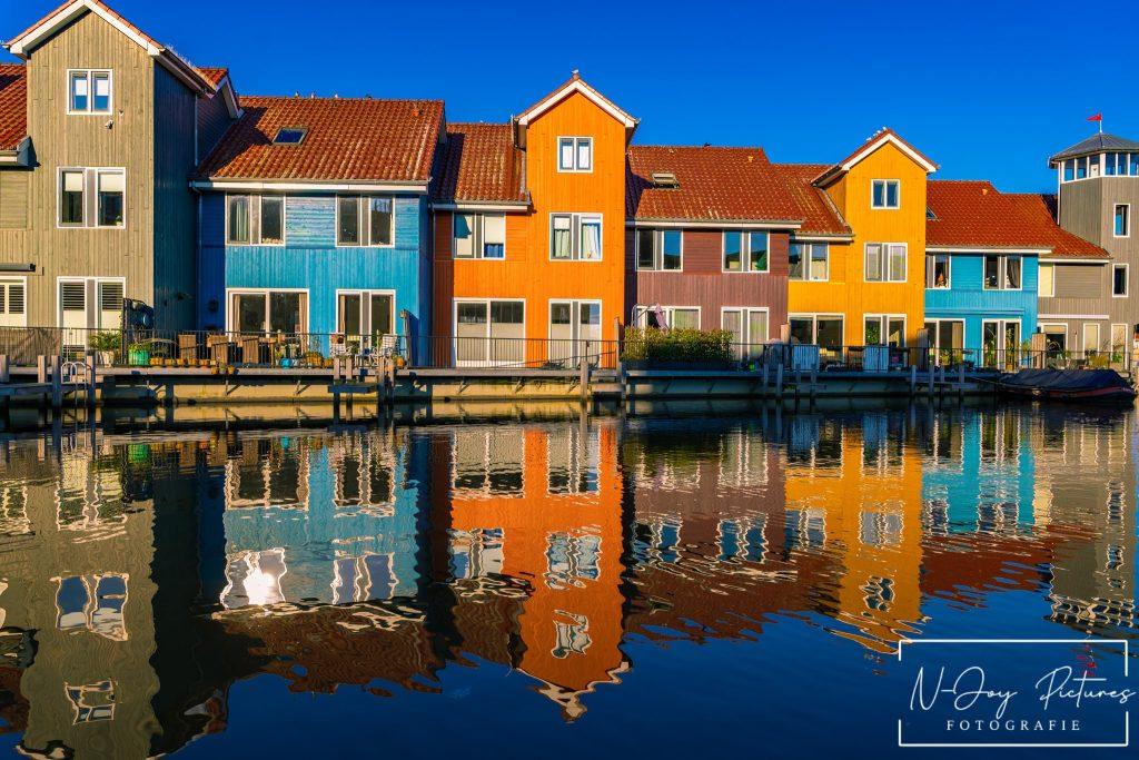 Levendige Plekken van Reitdiephaven Groningen Ontmaskerd! 12 Kleurrijke huisjes aan de Reitdiephaven in Groningen weerspiegelen in het kalme water, met een serene sfeer die perfect is voor stadsfotografie.